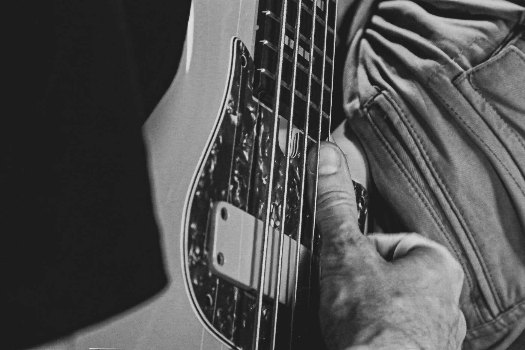 Closeup of bass strings being played with a thumb